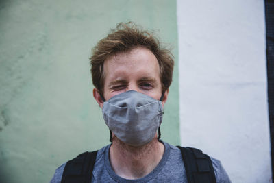 Male portrait with mask on in front of colorful wall.