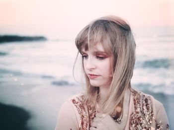 Portrait of beautiful woman at beach against sky