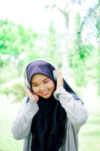 Portrait of young woman standing against trees