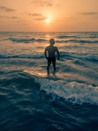 Man on beach against sky during sunset