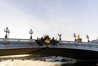 Statue of bridge over river against sky