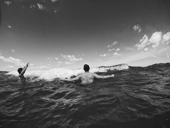 Men in sea against sky