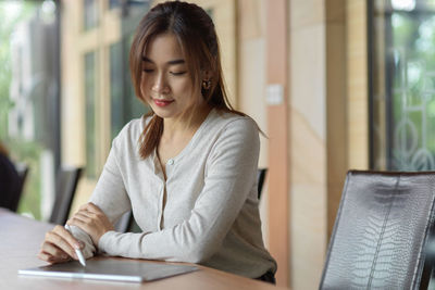 Young woman looking down while sitting on table