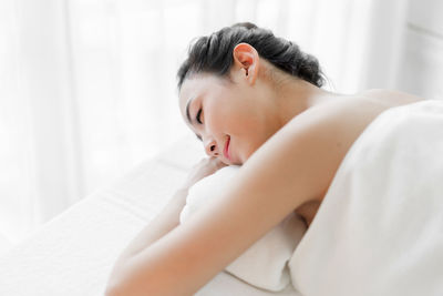 Side view of baby girl sleeping on bed at home