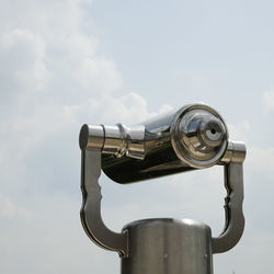 Low angle view of coin-operated binoculars against sky