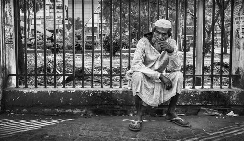 Full length of man sitting by fence