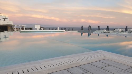 Scenic view of swimming pool by sea against sky during sunset