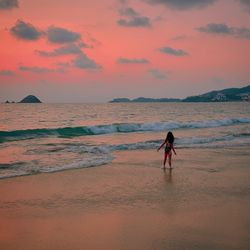 Woman on beach against sky during sunset