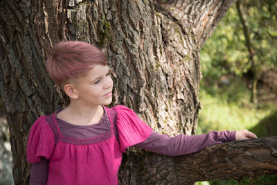 Teenage girl looking at tree trunk