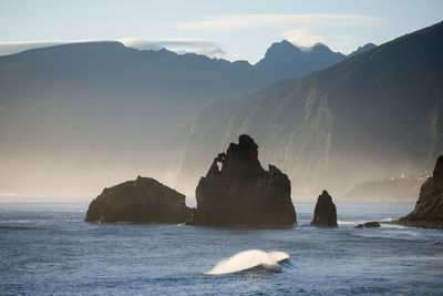 Scenic view of sea and mountains against sky