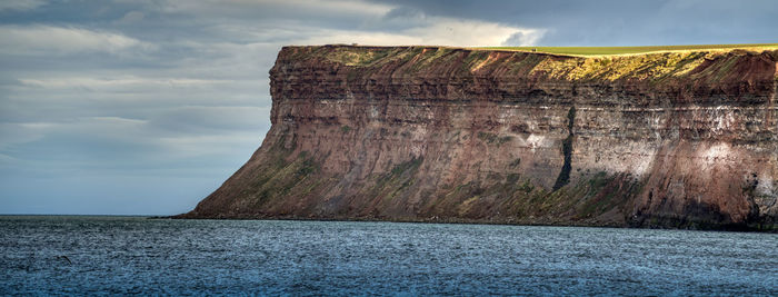 Rock formations by sea against sky