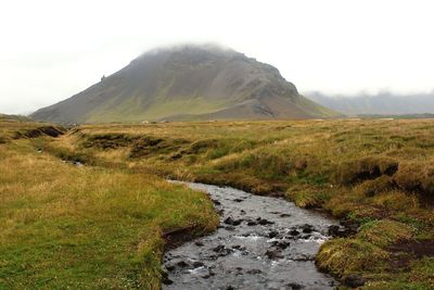 Scenic view of stream flowing amidst land against sky