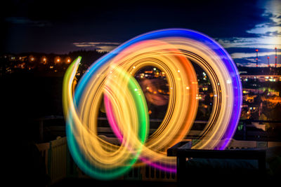 Multi colored light trails in city against sky at night
