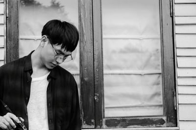 Young man standing against window