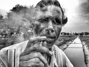 Portrait of man smoking bidi against sky