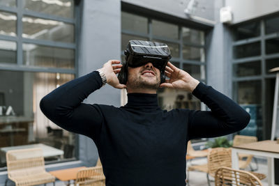 Smiling businessman using virtual reality headset while sitting at cafe
