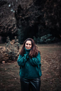 Smiling young woman standing on land in forest