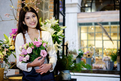 Portrait of smiling florist holding flowers in store