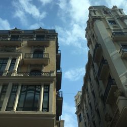 Low angle view of buildings against cloudy sky