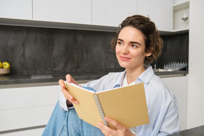 Portrait of smiling young woman reading book