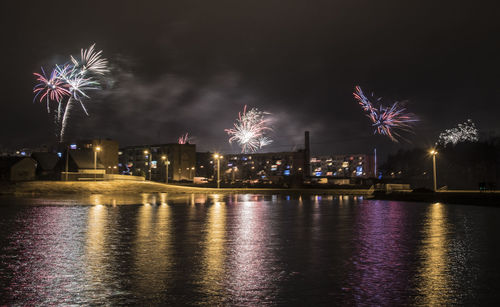 Firework display over river at night