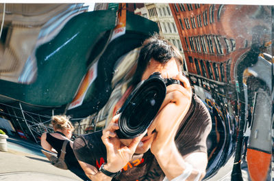 Reflection of man clicking selfie with camera