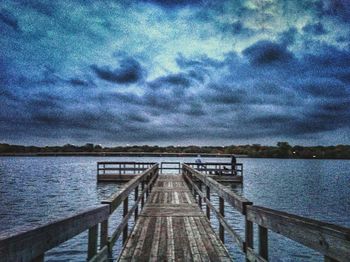 Pier on sea against cloudy sky