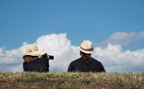 Rear view of people working on field against sky