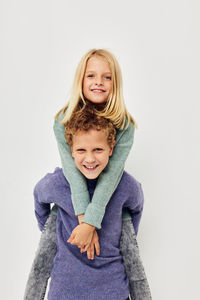 Portrait of smiling sibling against white background