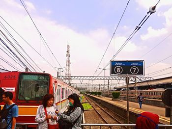 People at railroad station against sky