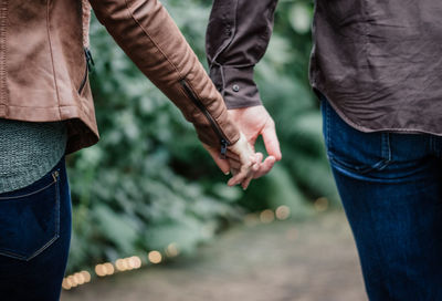 Midsection of couple holding hands