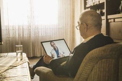 Rear view of man sitting on laptop