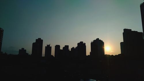 Silhouette buildings against sky during sunset