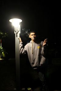 Man looking at illuminated lamp post at night