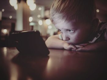 8close-up of boy using phone on table