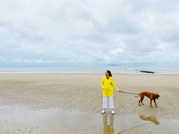 Woman standing with dog on beach