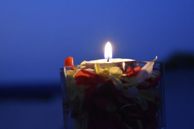 Close-up of lit candles against blue sky