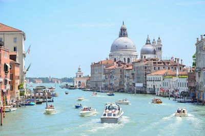 Boats in canal amidst buildings against sky