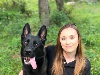 Portrait of smiling young woman with dog in forest