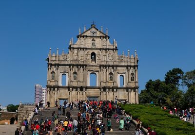 People at temple against clear blue sky