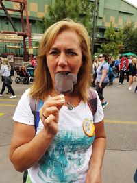 Portrait of woman holding ice cream in city