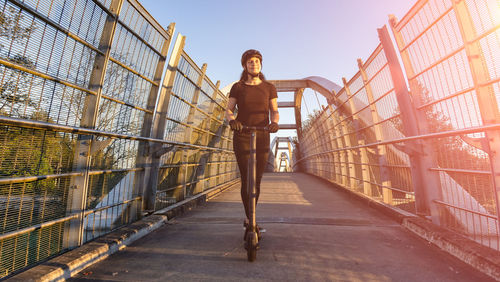 Woman standing on footbridge against sky