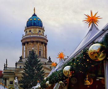 Illuminated christmas tree by building against sky in city