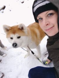 Portrait of woman with dog in snow
