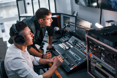 Conception of teamwork. two guys is indoors in the radio studio is busy by broadcast.