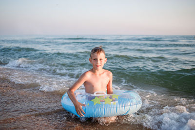 Portrait of shirtless boy in sea against sky