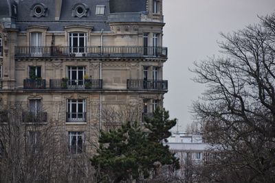 Building by trees against sky in city