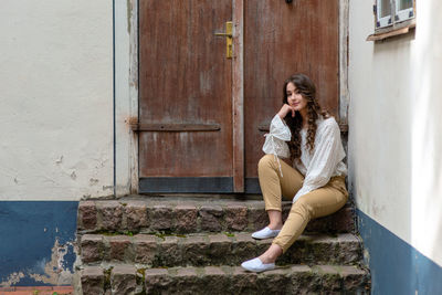 Portrait of woman sitting on steps against closed door