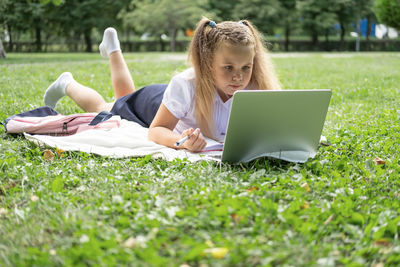 Woman using laptop while sitting on field
