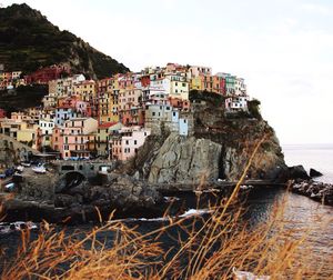 Buildings by sea against sky